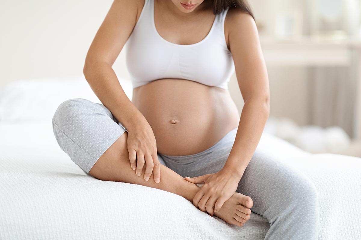 pregnant woman massaging her swollen foot varicose vein krampfadern removing berlin veincenter venenzentrum
