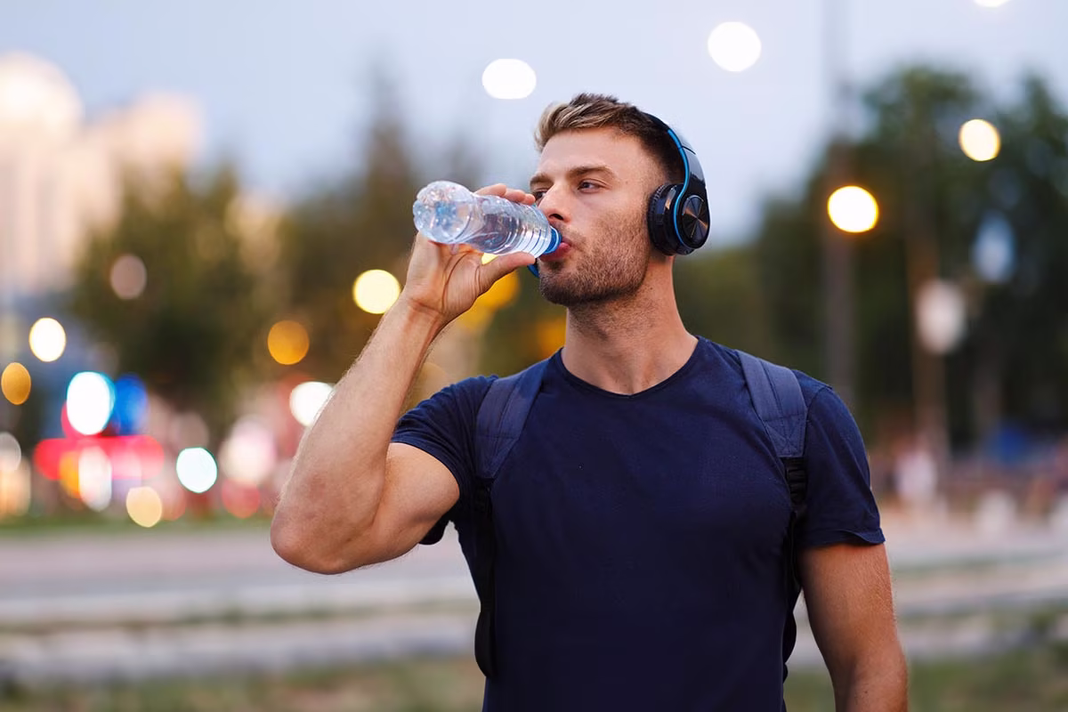 young-sports-man-making-break-and-drinking-water-after-long-sitting-or-standing-to-reduce-risk-of-krampfadern-bei-hitze young-sports-man-making-break-and-drinking-water-after-long-sitting-or-standing-to-reduce-risk-of-krampfadern-bei-hitze